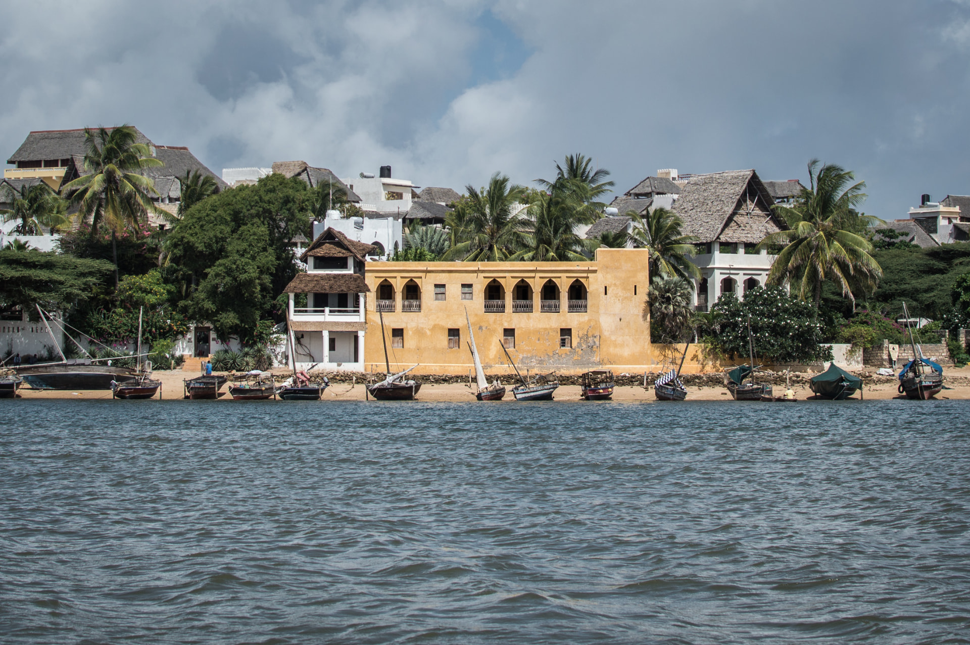 The seafront at Shela village, with dhows and ochre waterfront buildings along the sand