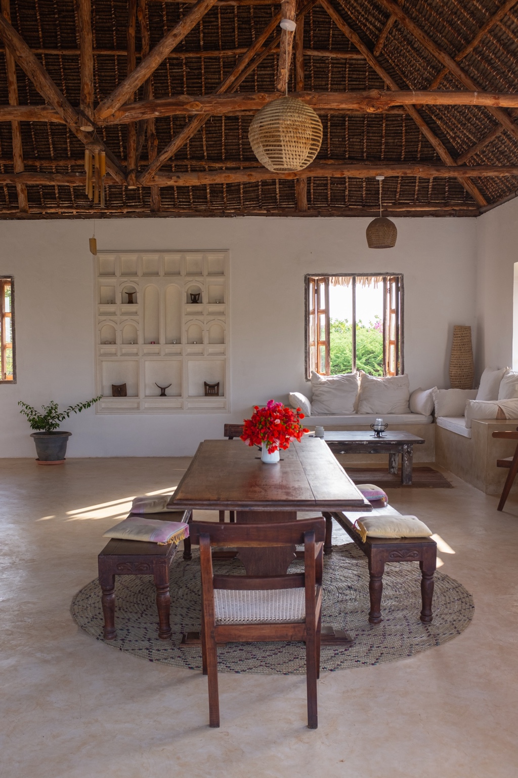 Living and dining room inside Mkoko, with a long timber table under a high thatched roof