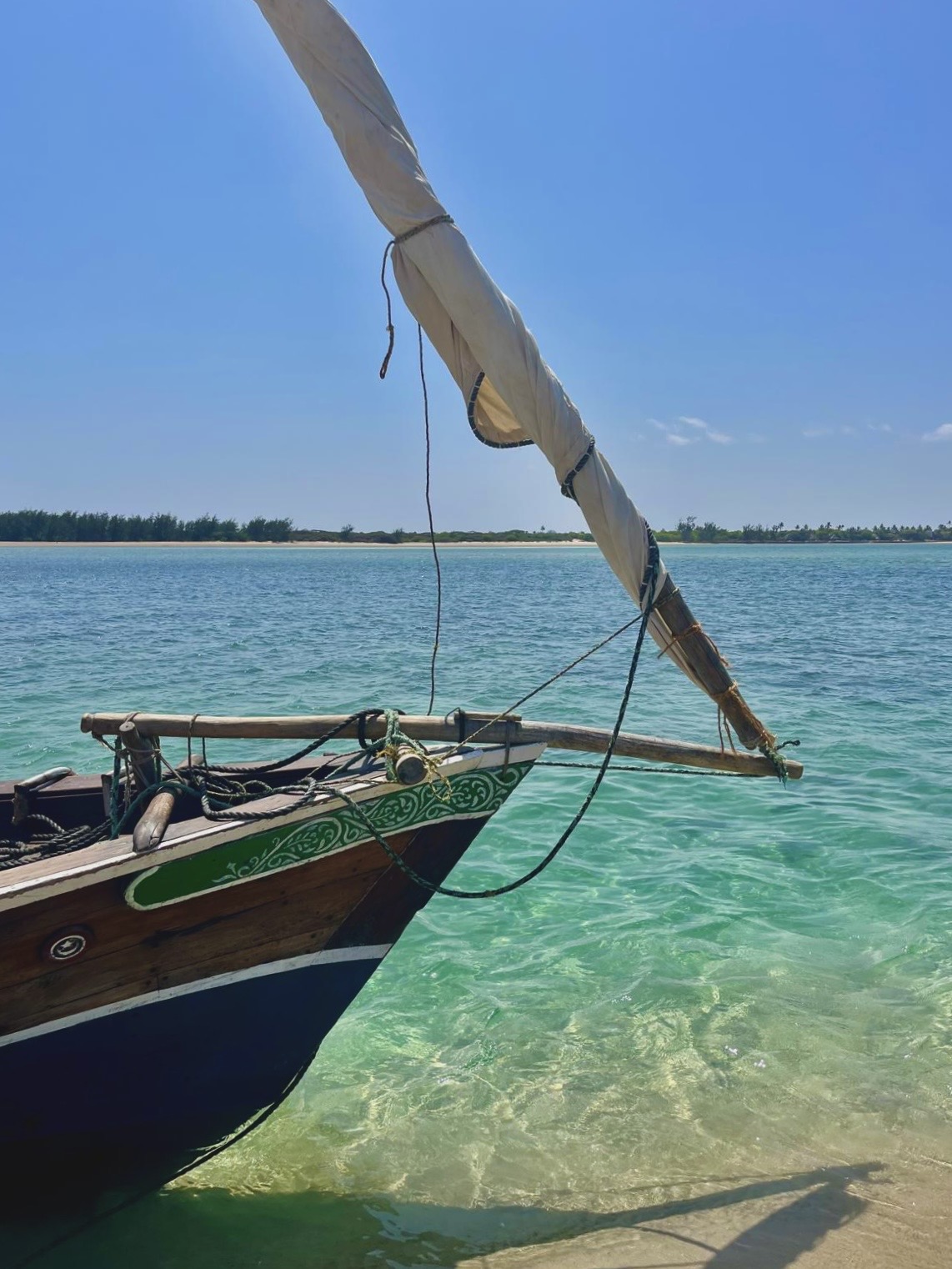 A traditional dhow sailing boat in clear turquoise water around Manda Island