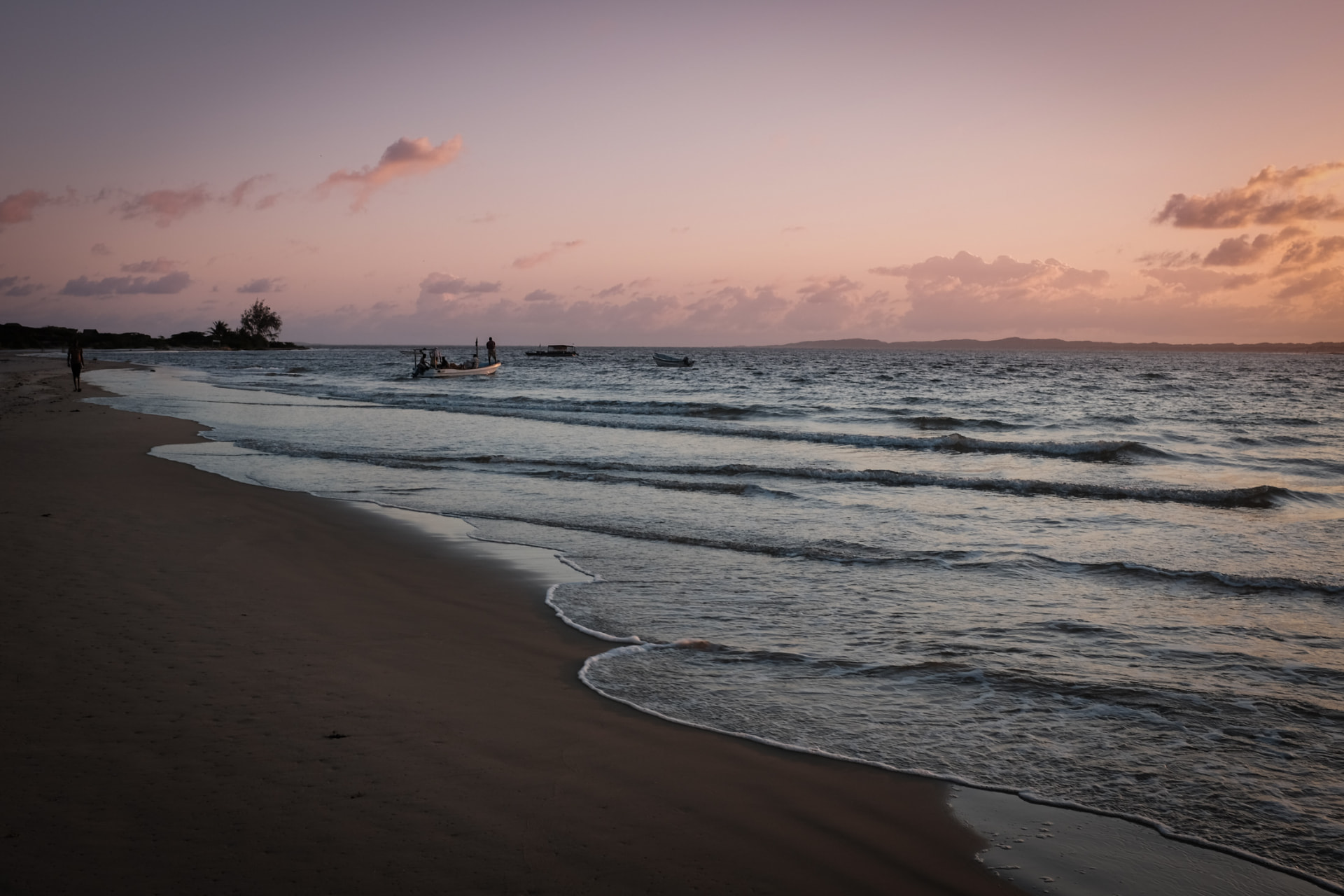 Sunset light over Manda beach with small boats on the water and the Lamu archipelago beyond