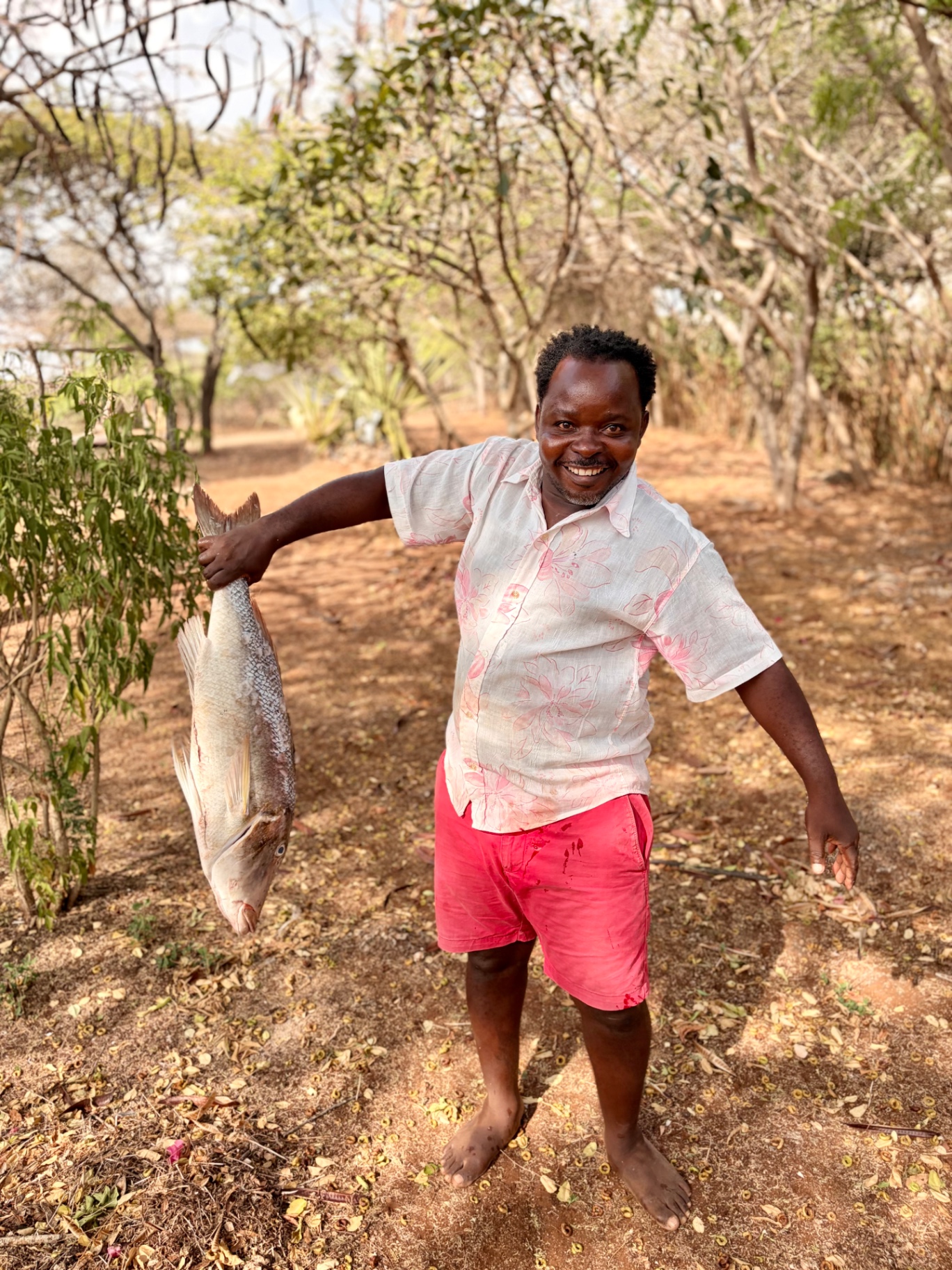 Idi holding a freshly caught fish among the trees beside Mkoko on Manda Island
