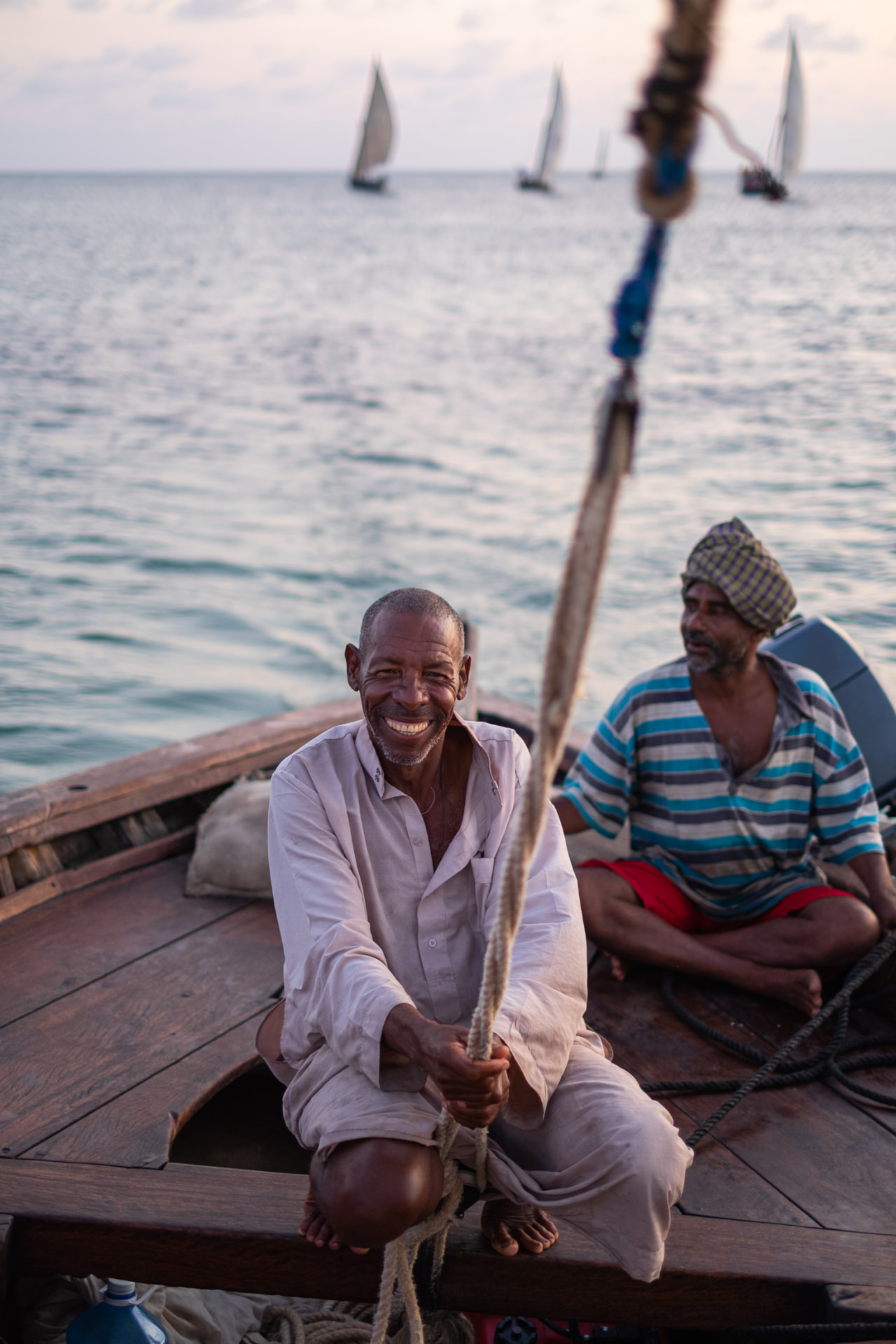 Two sailors working the rope of a traditional dhow under sail on the Indian Ocean off Lamu
