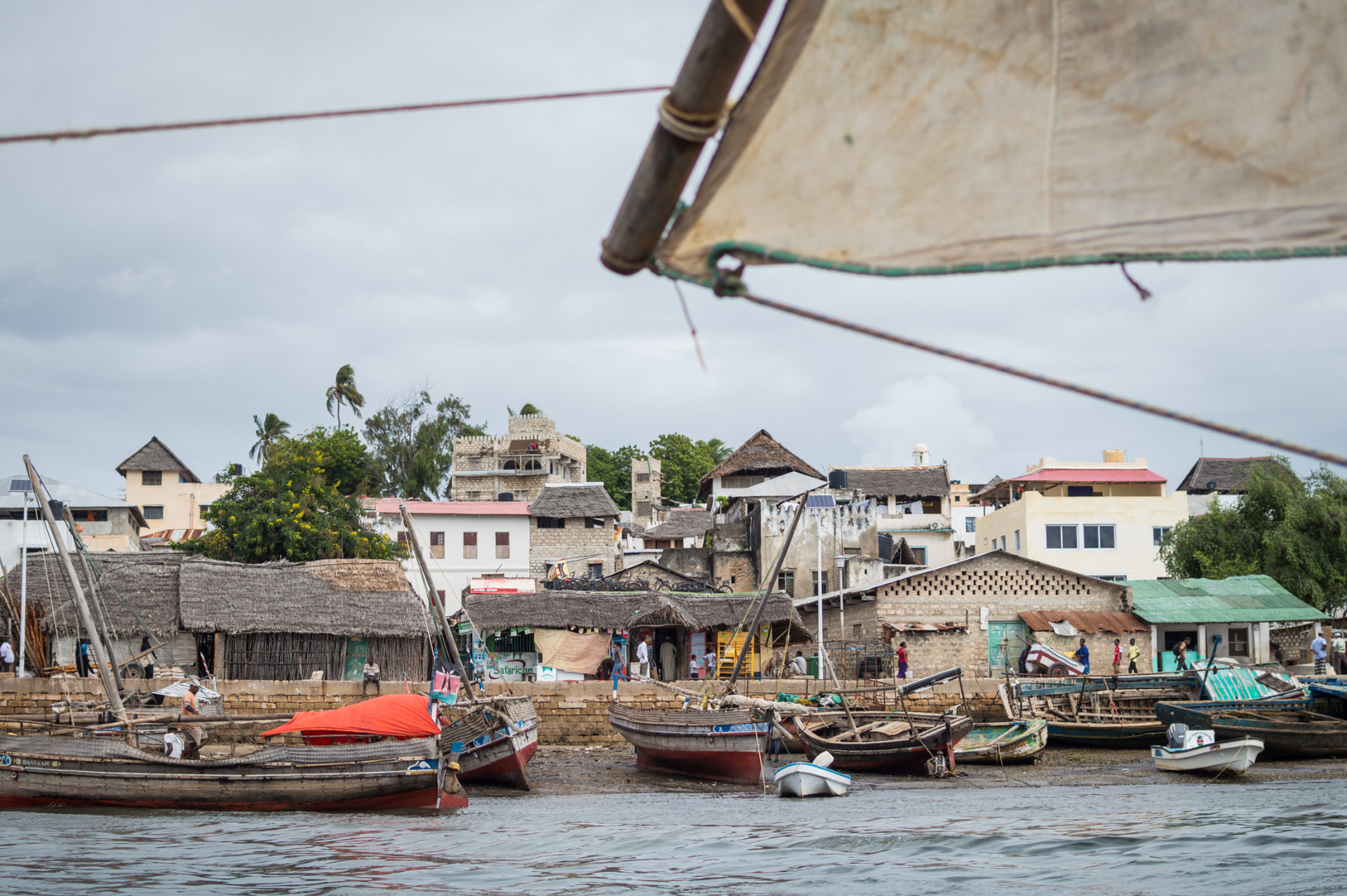 Lamu town waterfront with dhows drawn up on the sand below coral-stone buildings
