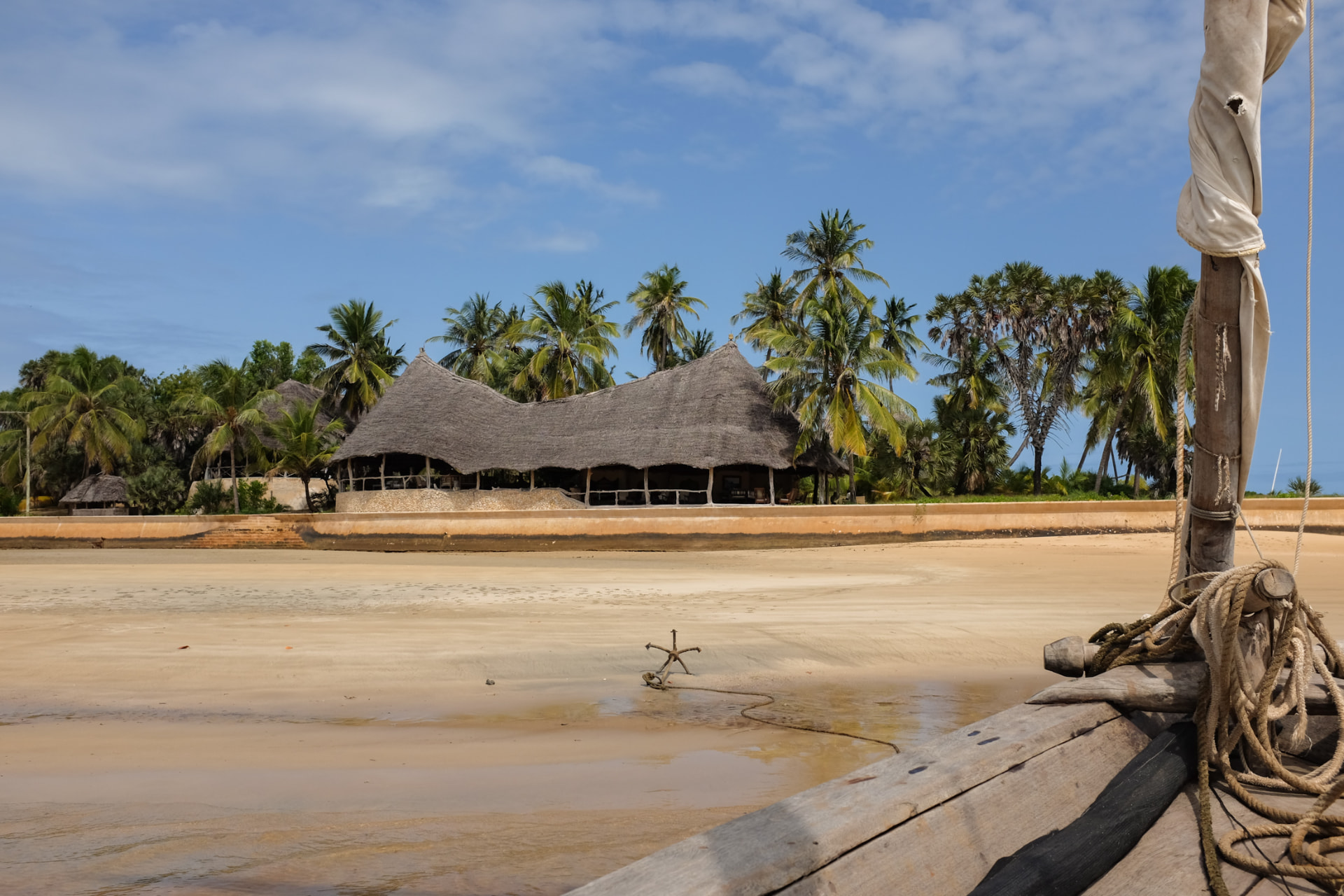 Wide sandy beach on Manda Island looking towards a makuti-roofed pavilion among palm trees